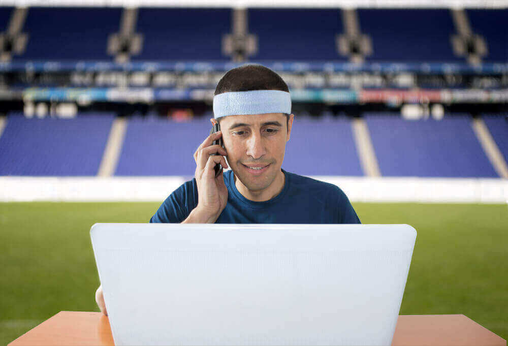 An image of a man in tennis gear on the phone, sports betting