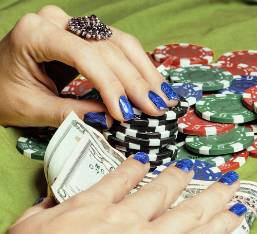 An image of hands of young caucasian woman with blue manicure at casino table close up, deep indigo design on nails