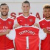 Arsenal footballers hold up the team jersey