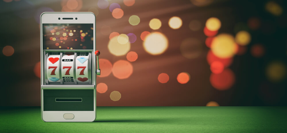 A smartphone displays a slot machine game on the screen in front of a bokeh background